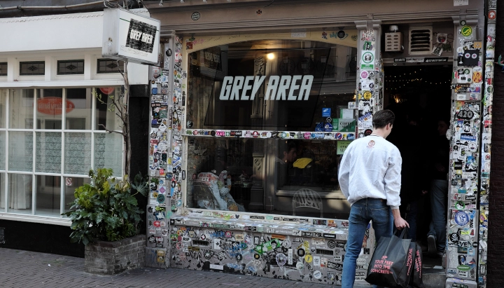 Cannabis-Coffeeshop in den Niederlanden Eingang eines Cannabis-Coffeeshops in den Niederlanden mit Grey-Area-Schild und stickerbedeckter Fassade.