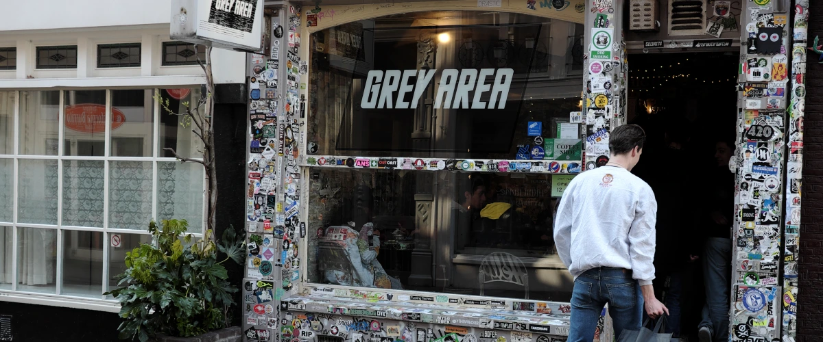 Cannabis-Coffeeshop in den Niederlanden Eingang eines Cannabis-Coffeeshops in den Niederlanden mit Grey-Area-Schild und stickerbedeckter Fassade.