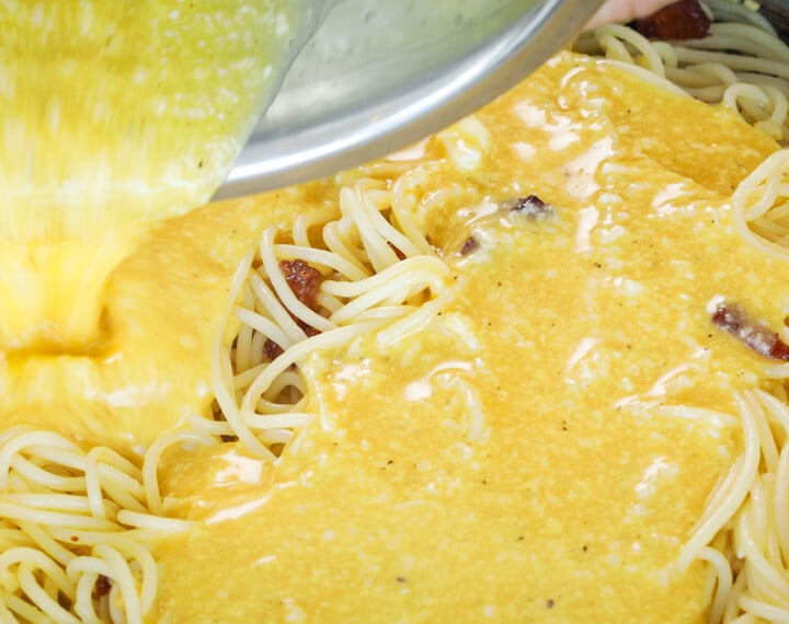 Eier-Käse-Mischung wird über heiße Spaghetti in der Pfanne gegossen, fünfter Schritt für eine Cannabis-Carbonara